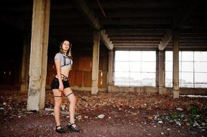 Girl wear on shorts and black erotic fetish underwear at abadoned factoty with brick. photo