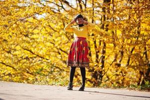 African american girl at yellow and red dress at golden autumn fall park. photo