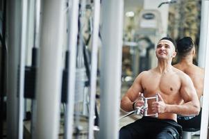 Muscular arab man training in modern gym. Fitness arabian men with naked torso doing exercises . photo