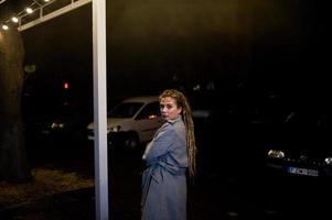 Girl with dreadlocks walking at night street of city. photo