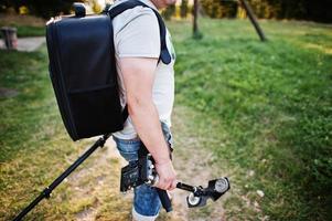 retrato de un fotógrafo con mochila, trípode y otros equipos. foto