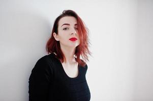 Red haired girl on black dress tunic against white wall at empty room. photo