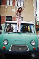 Amazing long legs with hig heels girl wear on hat sitting on roof of old retro minivan. photo
