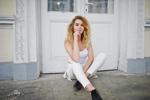 Stylish curly blonde model girl wear on white posing against old wooden door. photo