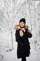 hermosa chica morena en ropa de abrigo de invierno. modelo con chaqueta de invierno y sombrero negro. foto