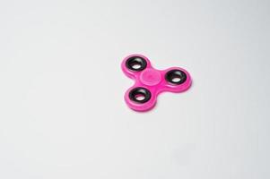 Close-up photo of a pink fidget spinner on a white background.