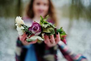 Ggirl holding wreath on hands at snowy forest in winter day. photo