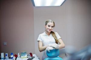 una dentista guapa posando con bata blanca en un gabinete moderno y bien equipado. foto