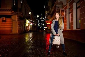 chica con rastas caminando por la calle de noche de la ciudad. foto