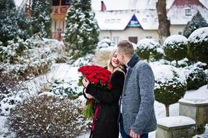 Loving couple in love at winter  day with large bouquet of 101 roses. photo