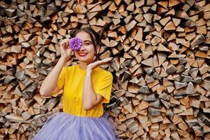 Girl in yellow shirt with violet aster flowers at hand behind eye. photo