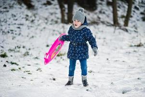 Cute little girl with saucer sleds outdoors on winter day. photo