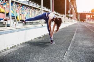 Portrait of a beautiful woman in sportswear stretching her muscles in the stadium. photo