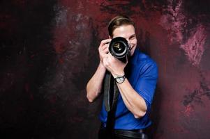 Studio portrait of stylish professional photographer man with camera, wear on blue shirt and necktie. photo