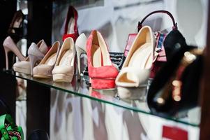 Huge variety of female shoes and bags of different colors on the shelves of the shop. photo