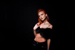 Fashion model red haired girl with originally make up like leopard predator isolated on black. Studio portrait. photo