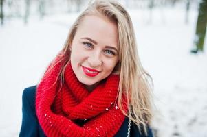 retrato de una chica rubia con bufanda roja y abrigo el día de invierno. foto
