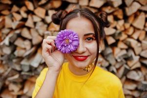 Girl in yellow shirt with violet aster flowers at hand behind eye. photo