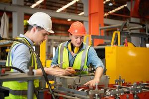 Two young engineers Testing and verifying the operation of the machines forming metal sheet tiles photo