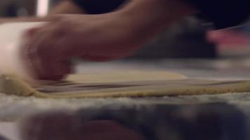 escena de bola de masa hervida. escena de laminación de masa de maestro pastelero. lleva la masa a la consistencia con un rodillo giratorio. video