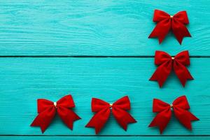 Frame of red bows on blue wooden background with copy space. photo