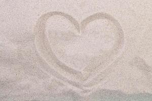 costa del mar. corazón de inscripción en la arena de la playa foto