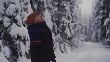 garçon regardant les arbres le jour de la neige. le garçon lève les yeux et regarde les arbres enneigés. video