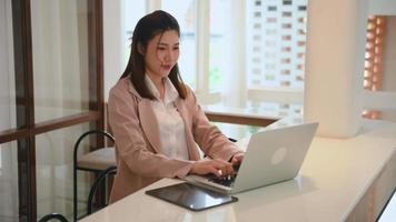 Asian woman using laptop computer at modern office with blurred background