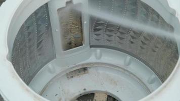 närbild av avkalkning av tvättmaskinstrumman med högtryckstvätt. delar och tillbehör inuti maskinen för att tvätta kläder som har tagits bort för att rengöra och ta bort smutsavkalkning. video