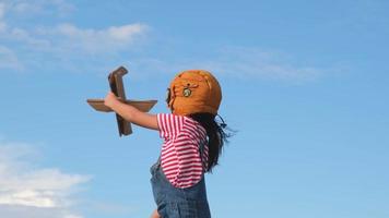 bambina sognatrice carina che gioca con aerei di cartone nel prato in una giornata di sole. bambino felice che gioca con l'aereo di cartone sullo sfondo blu del cielo estivo. concetto di immaginazione dei sogni d'infanzia. video