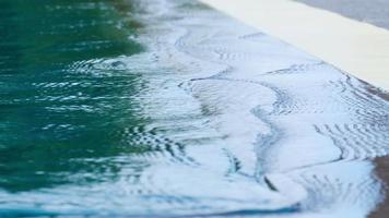 Nahaufnahme des weißen Beckenrandes mit Wasserwellen im Sommer als Hintergrund und Textur. video