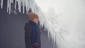 Child watching the view in front of icicles. Child standing in front of icicles enjoying snowy weather and scenery and looking around. video