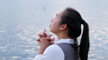 femme priant seule au coucher du soleil. une femme prie pour que Dieu bénisse de souhaiter avoir une vie meilleure. concept spirituel et religieux. video