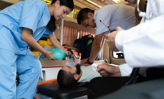 First aid assistance of the ambulance medical team with CPR method and hand-squeezed breathing apparatus photo