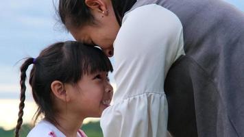 Die liebevolle Mutter küsst ein süßes lächelndes kleines Mädchen und umarmt sich am See. glückliche familie, mutter und kleine tochter, die sich im park glücklich fühlen. video