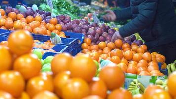 naranjas y otras frutas. los comerciantes organizan las frutas en el pasillo del mercado. video