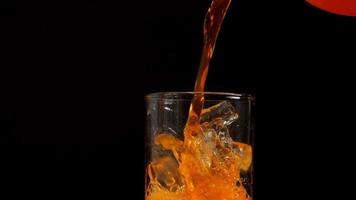 4k slow motion van jus d'orange gieten in glas close-up op zwarte achtergrond video