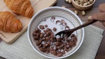 Top view of high frame rate slow motion hand stirring cereal with milk on wooden background, healthy breakfast concept. video