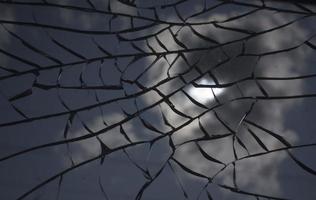 Broken glass over sky and sun behind the cloud background. photo