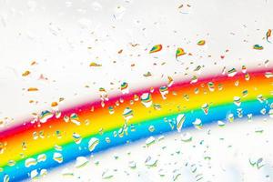 A rainbow behind a glass windows with water drops, Point of view, from behind the glass with drops. photo