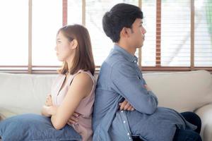 Relationship of young asian couple having problem on sofa in the living room at home, family having conflict argument with unhappy, man and woman with issue, failure and stress together. photo