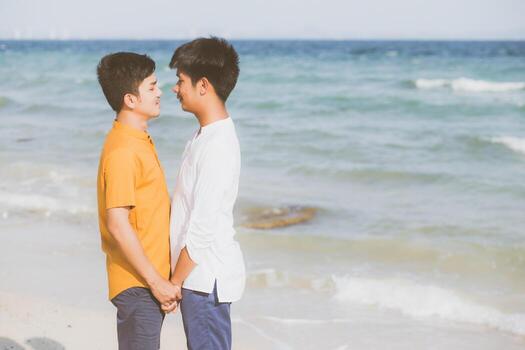 retrato homosexual joven pareja asiática de pie juntos en la playa en verano, asia gay tomados de la mano yendo al mar por placer y relajarse con romántico y feliz en vacaciones en el mar, lgbt con concepto legal. foto