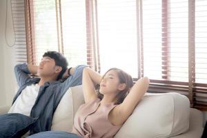 Young asian couple smile relax comfortable on sofa in the living room in holiday, family leisure and resting with happy in vacation on couch at home, lifestyle and wellbeing concept. photo