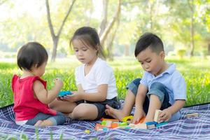 Little boy and girl is playing for idea and inspiration with toy block, kid learning with construction block for education, child activity and game in the park with happy in the summer. photo