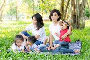 Beautiful young asian parent family portrait picnic in the park, kid or children and mother love happy and cheerful together in summer at garden, lifestyle concept. photo