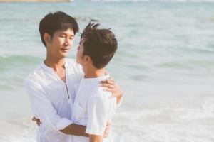 Homosexual portrait young asian couple standing hug together on beach in summer, asia gay going tourism for leisure and relax with romantic and happiness in vacation at sea, LGBT concept. photo