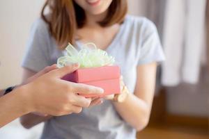 hermosa joven pareja asiática enamorada caja de regalo sorpresa en el dormitorio en casa, aniversario familiar con disfrute y romántico juntos esposa y esposo con relación, celebrando el concepto de día de san valentín. foto