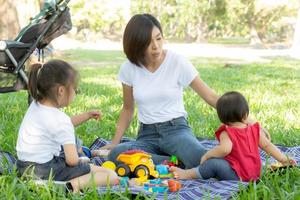 Beautiful young asian mom and daughter playing toy blocks for learning development happy and fun at park in summer, mother and kid cheerful activity together at garden in holiday, family concept. photo