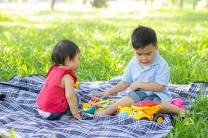 Little boy and girl is playing for idea and inspiration with toy block, kid learning with construction block for education, child activity and game in the park with happy in the summer. photo