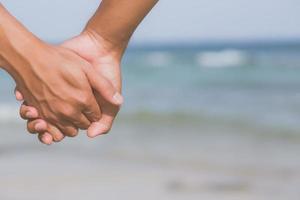 primer plano pareja gay asiática cogidos de la mano juntos en la playa con relax y ocio en verano, lgbt homosexual legal dos hombres felices y románticos en vacaciones, concepto de relación amante del sexo. foto